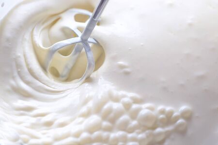 Whipping cream with a mixer. Bubbles on cream.の写真素材