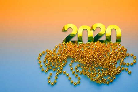 Happy New Year 2020. Illustration of shiny 2020 figures made of paper and Christmas tree toys, gold beads on a blue-orange backgroundの写真素材