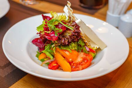 Salad of vegetables and herbs with cheese on a large white plate.の写真素材