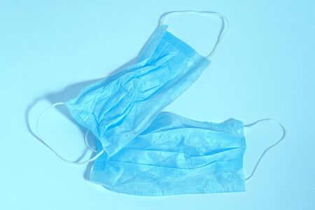A dented blue medical mask on an isolated blue background. Medical items in the fight against coronavirusesの写真素材
