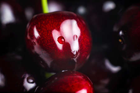 Glossy cherry with water drops on a dark background.の写真素材