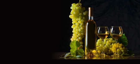 Grapes with a glass of wine on the table on a black background, a place for textの写真素材