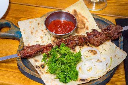 Barbecue on a skewer with tomato sauce, onions and herbs.の写真素材