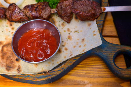 Barbecue on a skewer with tomato sauce, onions and herbs.の写真素材