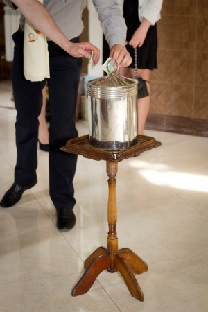 Inserting a banknote into offertory box.の写真素材