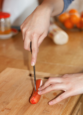 A chef cutting a sausage on a cutting boardの写真素材