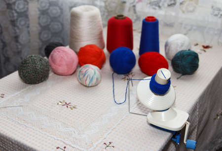 Process of winding coiler a blue yarn into a reel on background of a group of multicolored tangles...