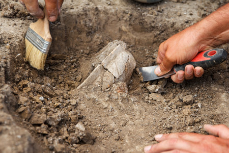 Archaeological excavations, archaeologists work, dig up an ancient clay artifact with special tools in soilの写真素材