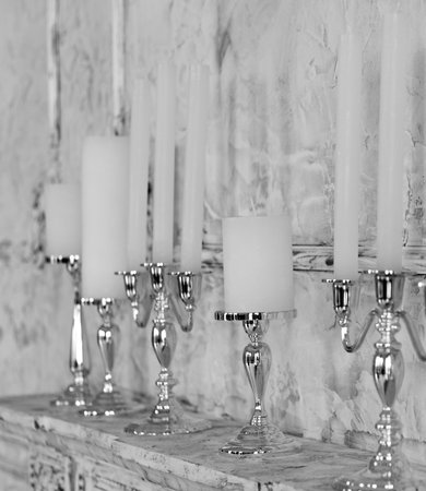 White candles in elegant candlesticks stand on a fireplace in the roomの写真素材