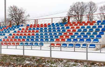 Places where fans sit, plastic chairs in a football stadium, in winter in snowy weather