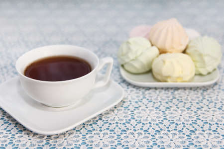 Traditional delicious brewed tea in a cup and air marshmallows lie on table, a sweet dessertの写真素材