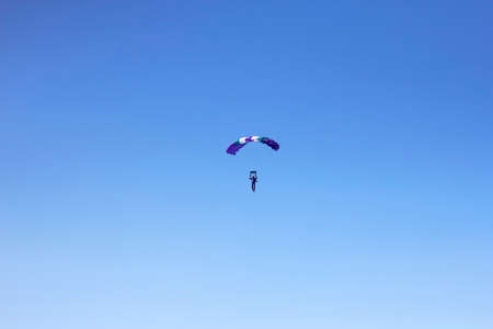 Flight of an experienced paratrooper with a professional parachute in the blue sky, orientation and landing on accuracyの写真素材