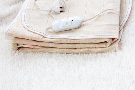 A warm two-sided new electric sheet, lies assembled, and on top of the sheet lie a temperature switch and a white fork. This is a quick and economical way to heat up in the cold season, in winterの写真素材
