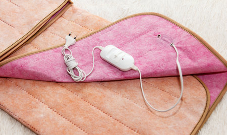 A warm beautiful two-sided new electric sheet, lies assembled, and on top of sheet lie a temperature switch and a white fork. This is a quick and economical way to heat up in cold season, in winterの写真素材