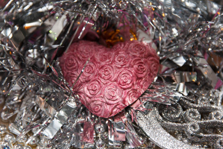 A pink beautiful heart with rose patterns surrounded by shiny silver tinsel. Scene conveys a festive atmosphere, suitable for celebrations or romantic occasionsの写真素材