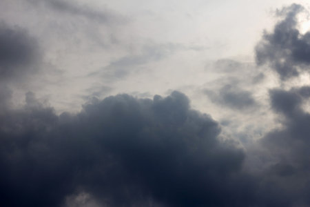 Dramatic view of a dark, ominous sky filled with heavy storm clouds. The moody, atmospheric lighting...