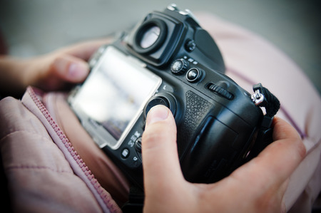 Female hands with dslr camera, reviewing images on camera LCD display closeupの写真素材