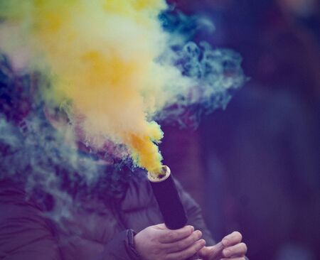 Colorful yellow smoke bomb on a festivalの写真素材