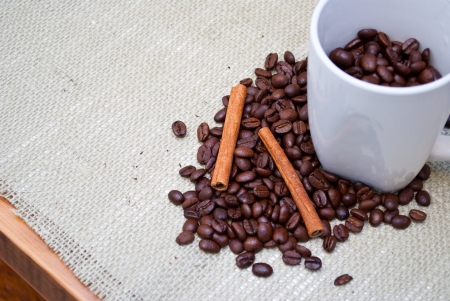 Coffee Beans and Cinnamon Sticks on a Woven Table Clothの写真素材