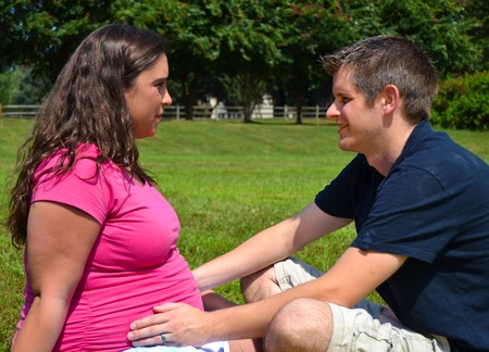 Expectant Couple Sitting in the Grassの写真素材