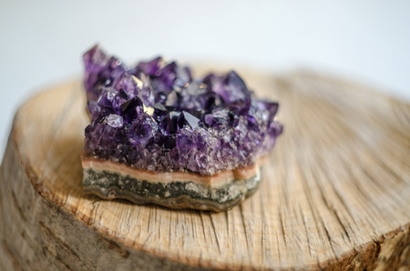 Raw violet amethyst rock on natural wood macro