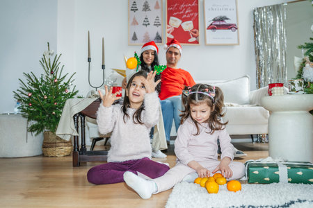 Children playing with tangerines near a Christmas tree, joyful family atmosphere in the living room. Festive mood, family awaiting Christmas and New Year, decorating the tree, unwrapping gifts, and enjoying time together.の写真素材