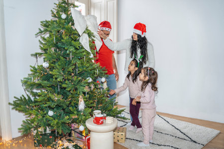 The family enjoys quality time near the decorated Christmas tree. The children unwrap presents, play, and cherish the festive atmosphere of Christmas and New Year.の写真素材