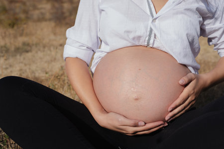 Pregnant Woman in Nature in Autumn, Tender Moment of Expectationの写真素材