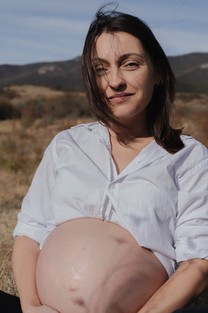 Pregnant Woman in Nature in Autumn, Tender Moment of Expectation