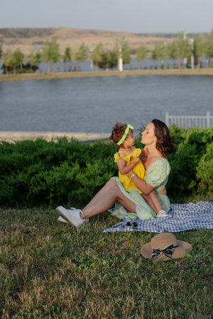 Mother and daughter enjoying a joyful picnic, running in the park, playing by the lake, and having fun in a lavender field. Bright outfits, summer vibes, and heartfelt family moments.の写真素材