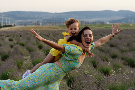 Mother and daughter enjoying a joyful picnic, running in the park, playing by the lake, and having fun in a lavender field. Bright outfits, summer vibes, and heartfelt family moments.の写真素材