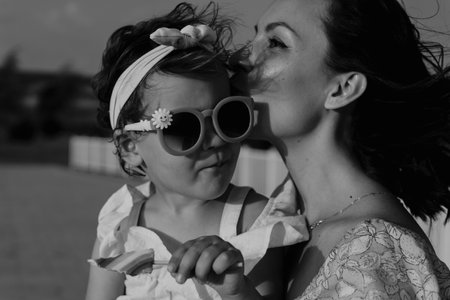 Mother and daughter enjoying a joyful picnic, running in the park, playing by the lake, and having fun. Bright outfits, summer vibes, and heartfelt family moments.の写真素材