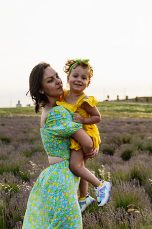Mother and daughter enjoying a joyful picnic, running in the park, playing by the lake, and having fun in a lavender field. Bright outfits, summer vibes, and heartfelt family moments.の写真素材