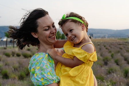 Mother and daughter enjoying a joyful picnic, running in the park, playing by the lake, and having fun in a lavender field. Bright outfits, summer vibes, and heartfelt family moments.の写真素材