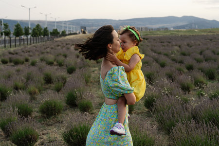 Mother and daughter enjoying a joyful picnic, running in the park, playing by the lake, and having fun in a lavender field. Bright outfits, summer vibes, and heartfelt family moments.の写真素材