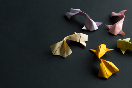 Oval frame figure of handmade paper craft origami gold koi carp fishes on black background. Side viewの写真素材