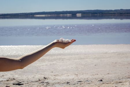 Female hand holding natural salt crystals on the background of a salt lake, side viewの写真素材
