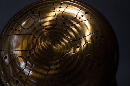 Golden hang drum on a black background, near view, closeup, selective focus
