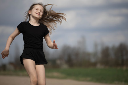 Little blonde girl runs fast along the roadの写真素材