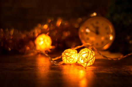Rattan balls garland on a wooden surface on the background of the clock in the gold toning. Christmas backgroundの写真素材