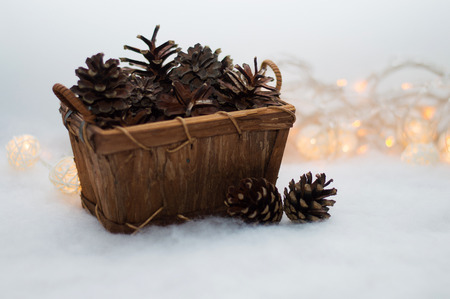 a basket of pine cones on the background lights garland and faux snowの写真素材