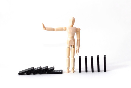 the man stops falling dominoes on white backgroundの写真素材