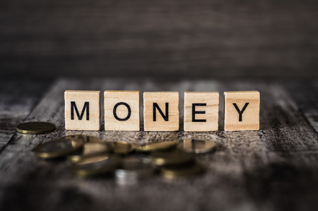 the word money made of bright wood cubes with black letters of the English alphabet and randomly scattered the coins of the Belarusian currency on dark wood backgroundの写真素材