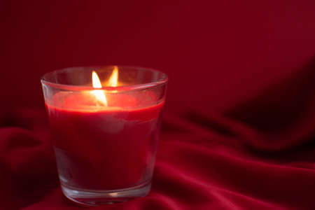 Red candle lit on red backgroundの写真素材