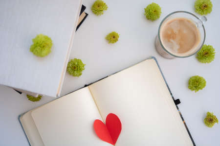 Open notebook with a red heart and a cup of coffee on a white backgroundの写真素材