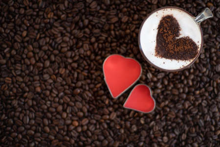 Cup of coffee with heart shape on coffee beans background, top view.の写真素材