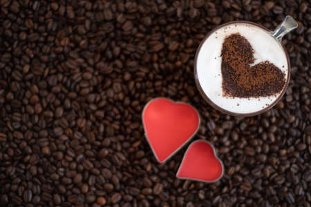 Cup of cappuccino with heart shape on coffee beans backgroundの写真素材