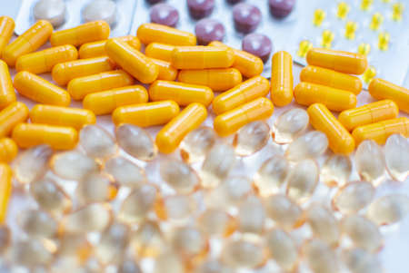 Close up of yellow and orange pills on white background. Focus on foreground.