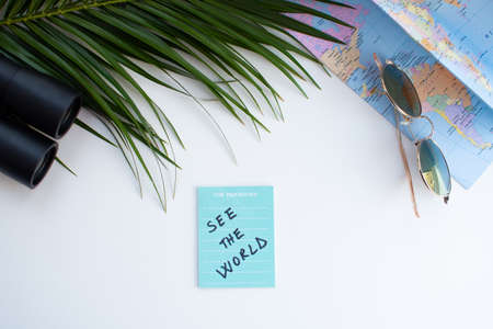 Top view of travel accessories on white background with palm leaf and world mapの写真素材