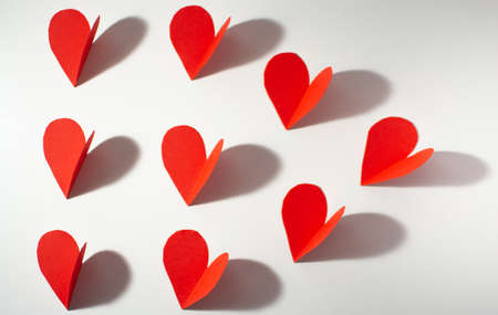 Red paper hearts on a white background. The concept of Valentine's Day.